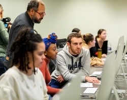 AC_HBO_700x550.jpg Three students and a professor looking at a computer screen (screen not visible)