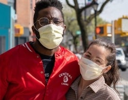 AC_MEL_700x550.jpg A man and woman wearing masks stand next to each other and smile at the camera