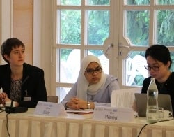 Milton Wolf 700 x 550.jpg Three people sitting at a conference table speaking and listening