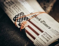 NYT Unsplash Jon Tyson.jpg A printed New York Times rolled up, wrapped in a rubber band
