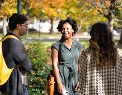 Sanjay Flo Devo 700 x 550.jpg Three students standing in a circle on a fall day outside. One is laughing.