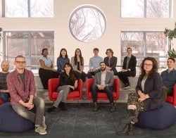 CIND 700 x 550.jpg Two professors and ten students seated in a horseshoe shape with a wall of windows behind them