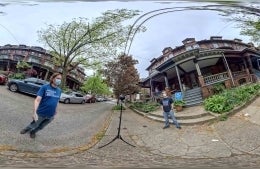 Distorted image of a VR camera on the street in Philadelphia with two men wearing protective masks standing around it