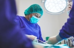 Nurse in full protective gear in an operating room performing surgery, photo credit Artur Tumasjan / Unsplash