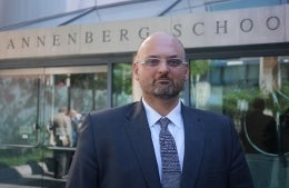 Marwan Kraidy in a suit and tie standing in front of the Annenberg School for Communication. The picture is from the chest up. 