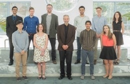 In the top row from left to right is Prateekshit Pandey, Eric Forbush, Zane Cooper, Mohammed Salih, Sean Fischer and Hanna Morris. The bottom row is Kwanho Kim, Celeste Wagner, Dean Michael X. Delli Carpini, Sanjay Jolly and Leann Siegel. They are dressed semi-formally and are in a well-lit area for the photo.