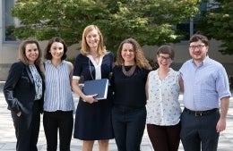 Group photo of students Megan Genovese, Stefanie Gratale, Elissa Kranzler, Hanna Morris, and John Vilanova, and Director Kim Woolf in a line smiling for the picture