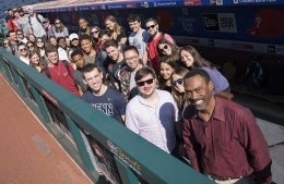 Doug Glanville, in front, poses with multiple students in a cluster behind him