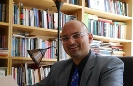 Marwan Kraidy smiling. He is seated in front of a bookshelf