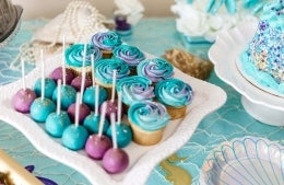a plate of cake pops and cupcakes in blues and purples