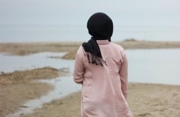 Photo of a woman wearing a scarf facing the water; photo credit: Ifrah Akhter / Unsplash