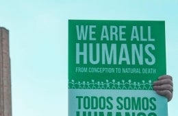Sign being held up that reads we are all humans; photo credit: Maria Oswalt / Unsplash