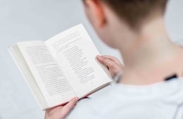Photo of an individual reading a book, photo credit Christian Wiediger / Unsplash