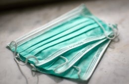 three green surgical face masks fanned on top of one another on a table