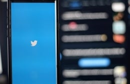 Twitter logo on phone with blurred social feed in background; photo by Joshua Hoehne on Unsplash