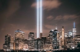 Manhattan skyline at night with two beams of light shooting up to represent the Twin Towers, photo credit Lerone Pieters / Unsplash