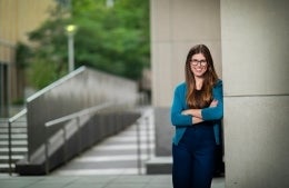 AvaKikut.jpg Ava Kikut smiling with her arms crossed and leaning against an exterior wall of the Annenberg School building