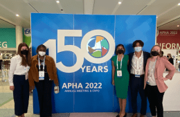Students pose in front of a banner reading APHA 2022