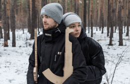 Students Vadym Beilakh and Sofia Chygyryn stand in a snowy forest holding wooden replicas of weapon