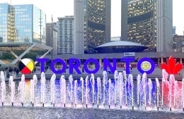 Fountain and Toronto sign in Nathan Phillips Square with buildings behind it