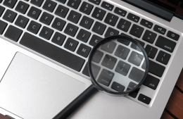 A magnifying glass sits on a laptop keyboard
