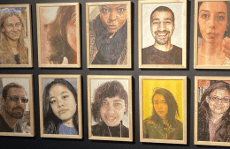 10 framed portraits hang on a black wall