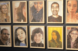 roopa-1.png 10 framed portraits hang on a black wall