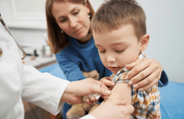 Doctor placing medical bandage a on child's arm after vaccination