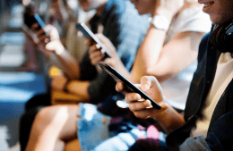 People sitting side by side holding and looking down at smartphones