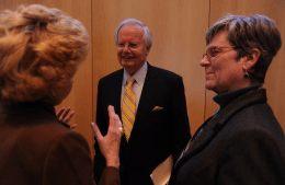 Bill Moyers smiling and conversing with two people