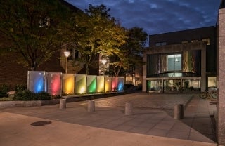 Walnut Street facade of the Annenberg School for Communication Building at night with rainbow-lit glass panels