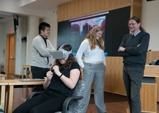 Student seated wearing virtual reality headset while three other students stand behind her