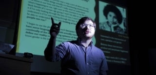 Student John Vilanova speaking in a dark room while standing in front of a bright screen