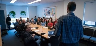 Lee Defense Room 300 FWF.jpg Man viewed from behind as he speaks to a long table full of people