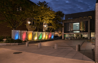 angled view of Annenberg School during the evening with colorful glass lighting panels on the left