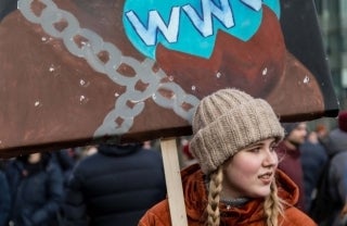 woman wearing a knit hat and holding a protest sign