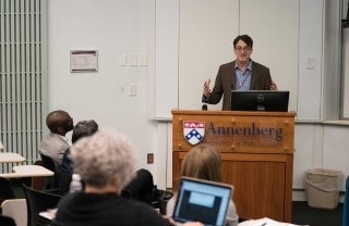 Victor Pickard standing at a podium with the Annenberg logo, with audience members watching