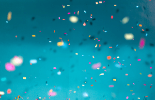 confetti falling in front of teal background, photo credit Jason Leung / Unsplash