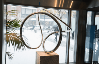 close view of metal spiral sculpture in Annenberg front lobby on a winter day with snow falling