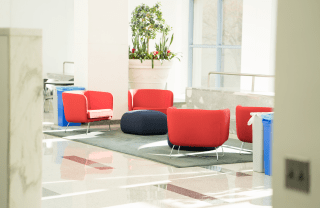 view of a white room with red chairs, white tiles, and a large potted plant