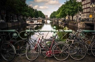 Photo of bikes along Amstel River in Amsterdam, The Netherlands, photo credit @jacegrandinetti / Unsplash.