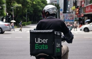 person wearing a helmet, riding on a bike, and carrying an Uber Eats backpack, photo credit @benjamin_1017 / Unsplash