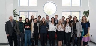 Group of students with two professors posing in the Annenberg Plaza lobby