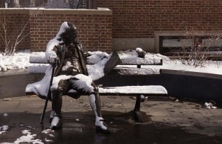 statue of Ben Franklin sitting on a bench during winter 