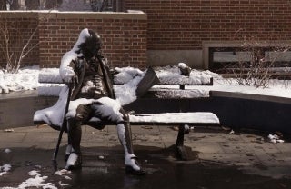 statue of Ben Franklin sitting on a bench during winter