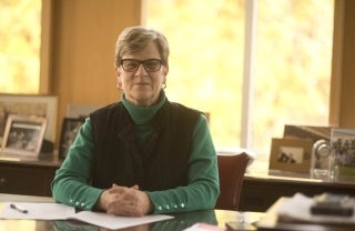 Kathleen Hall Jamieson sitting behind a desk with her hands clasped on the desk. She is posing for the photo.