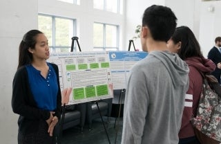 Angela Ip talking to two attendees of the thesis poster event