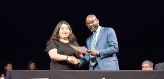 Dean Jackson shaking a student's hand and giving her a certificate at graduation