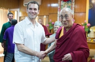 Emile Bruneau shakes hands while Dalai Lama as they both smile for the picture