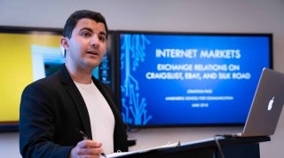 Jonathan dissertation 1920 x 1070.jpg Student speaking with screen behind that reads "Internet Markets: Exchange Relations on Craigslist, Ebay, and Silk Road"